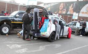 People sell clothes displayed on their car by the side of a busy road in  Harare, Zimbabwe, Tues …