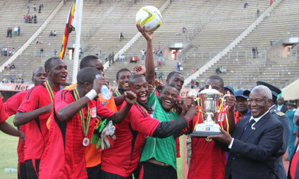 Minister of Defence Syndney Sekeramayi poses a photo with the Defence Force football team displaying their trophy after they beat Caps United 2 0 at National Sports Club. Pic Tafadzwa Uf