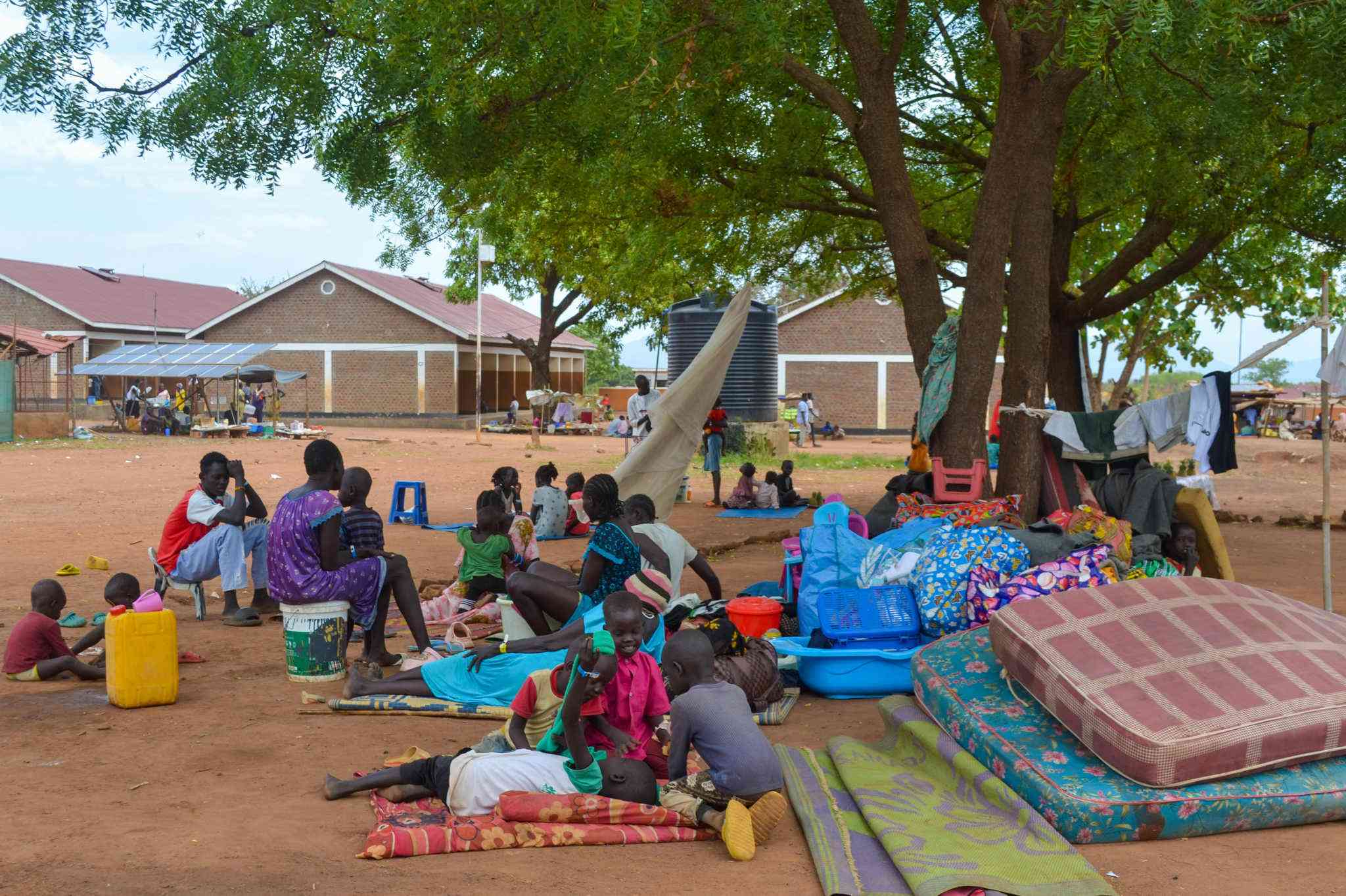 Newly arrived refugees wait with their belongings at Nyumanzi Reception Centre. Many have fled recent flare-ups of violence in South Sudan and Sudan. As donor funding dwindles, reception centers like Nyumanzi are struggling to accommodate growing numbers of arrivals.
